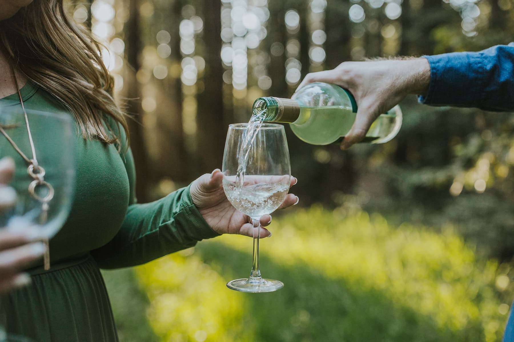 Glen pouring a bottle of white wine into Heather's glass