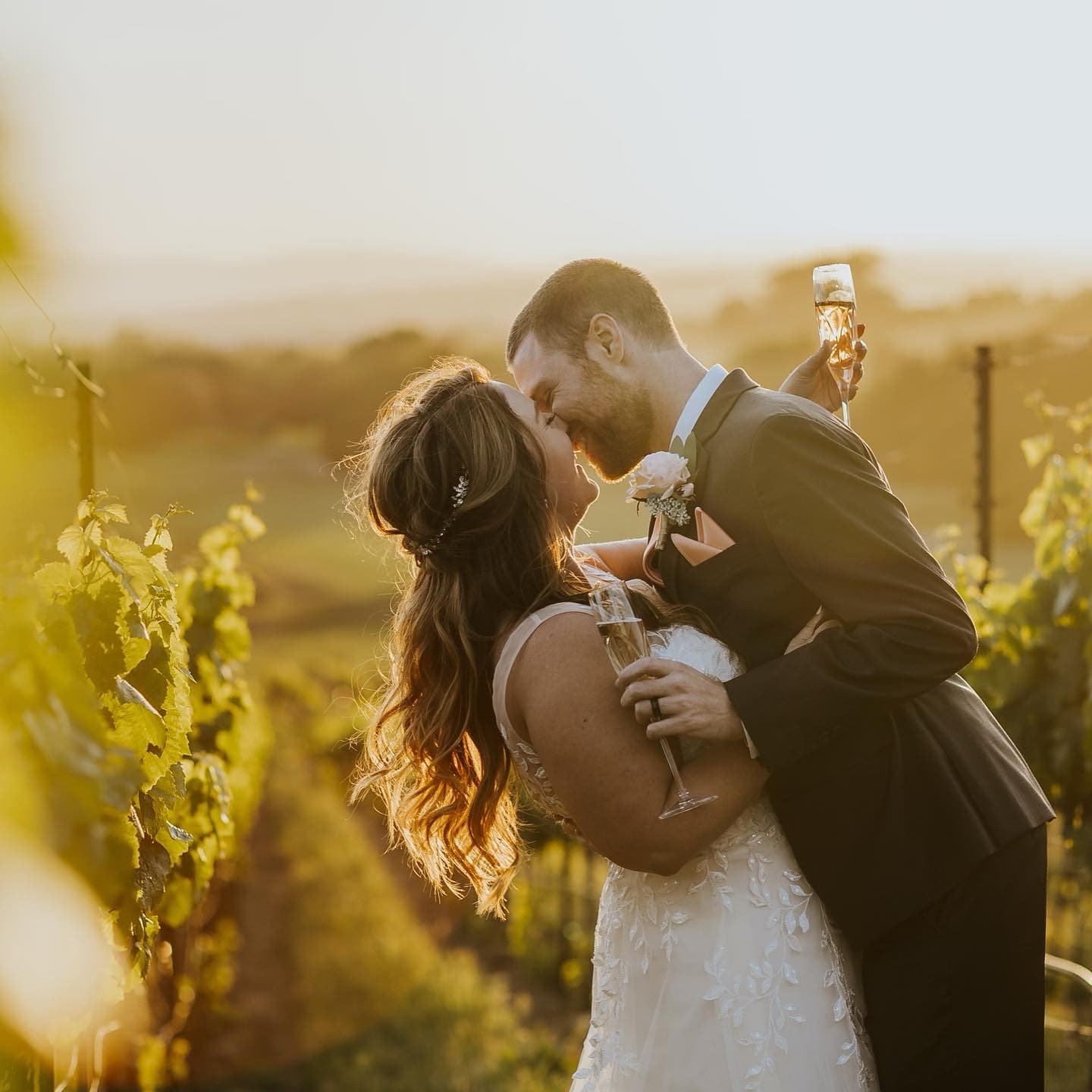 Glen and Heather standing in vineyards with a sunset in the background